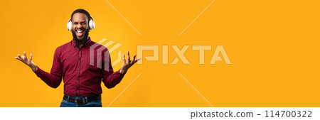 Online Music. Excited african american guy wearing white headset and dancing with joy isolated on yellow studio wall, copy space Online Music. Excited african american guy wearing white headset and dancing with joy isolated on yellow studio wall, copy space 114700322