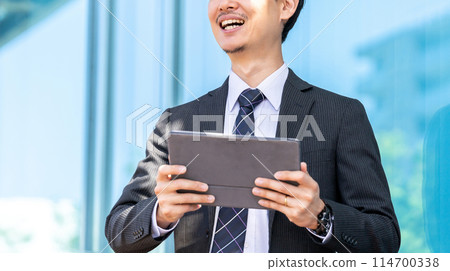 Smiling male businessman using a tablet 114700338