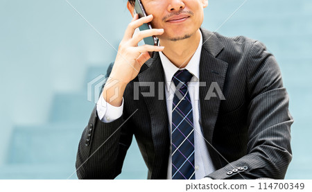 微笑的男性商人在智慧型手機上交談 微笑的男性商人在智慧型手機上交談 114700349