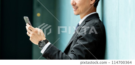 Smiling male businessman looking at smartphone screen Smiling male businessman looking at smartphone screen 114700364
