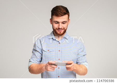 Young guy playing games on his phone and having fun, panorama, free space 114700386