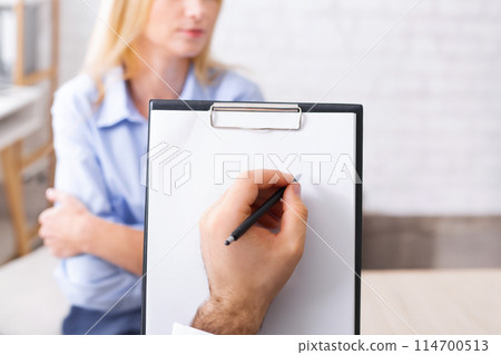 Psychotherapist clipboard. Doctor taking notes about health status of depressed millennial woman, closeup 114700513