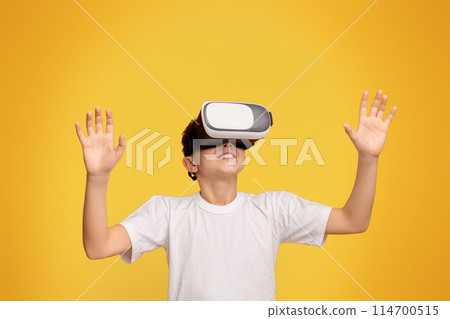Augmented reality at home. Teen boy enjoying 3D technology in virtual reality headset, orange panorama background 114700515