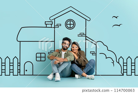 Indian man and woman are sitting next to each other in front of a drawing. They appear engaged in conversation or contemplation. The drawing, not fully visible, seems to be intricate and detailed. 114700863