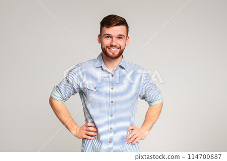 Portrait of smiling guy with hands on hips on beige background, panorama, copy space Portrait of smiling guy with hands on hips on beige background, panorama, copy space 114700887