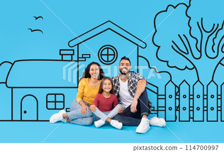 A happy middle eastern family consisting of a mother, father, and young daughter are sitting closely together, smiling, with a charming illustration of a house behind them 114700997