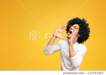 Young african-american man yelling on orange background with empty space 114701087