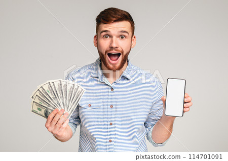 Happy to be reach. Surprised millennial guy with money and cellphone on studio background, blank space, panorama 114701091