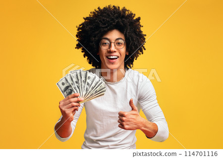 Saving money concept. Happy african-american guy holding bunch of money and showing thumb up gesture, orange background Saving money concept. Happy african-american guy holding bunch of money and showing thumb up gesture, orange background 114701116