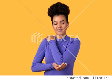 Portrait of Hispanic woman with dark wavy hair having trauma after car accident, feels pain in elbow, trapped nerves, rheumatoid arthritis. Indoor studio shot isolated on yellow background. 114701138