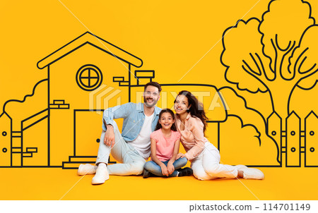 A family of three, consisting of two parents and daughter, are seated on the ground in front of drawn suburban house on yellow wall background A family of three, consisting of two parents and daughter, are seated on the ground in front of drawn suburban house on yellow wall background 114701149