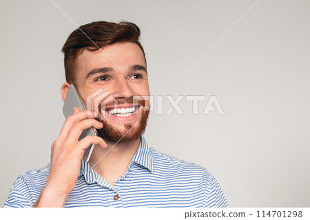 Portrait of young man talking on cellphone and smiling on studio background, panorama, copy space 114701298