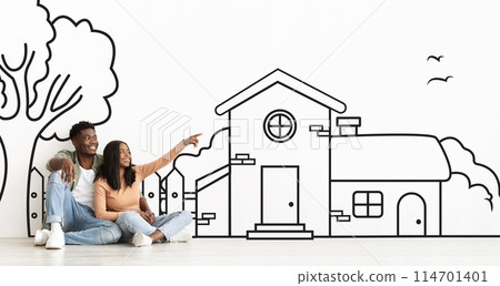 Joyful African American couple planning their dream home against a hand-drawn house sketch on white wall Joyful African American couple planning their dream home against a hand-drawn house sketch on white wall 114701401