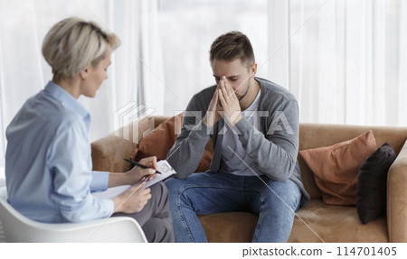 Depression Counseling. Desperate Man Telling About Unhappy Life While Professional Psychologist Taking Notes During Appointment In Office. Selective Focus Depression Counseling. Desperate Man Telling About Unhappy Life While Professional Psychologist Taking Notes During Appointment In Office. Selective Focus 114701405