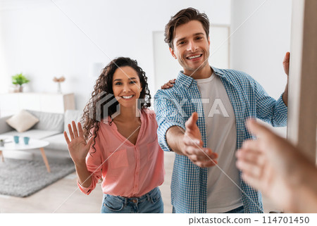 Portrait of cheerful couple inviting guests to enter home, happy young guy and lady standing in doorway of modern flat, looking out, man shaking hands, meeting new neighbors or friends Portrait of cheerful couple inviting guests to enter home, happy young guy and lady standing in doorway of modern flat, looking out, man shaking hands, meeting new neighbors or friends 114701450