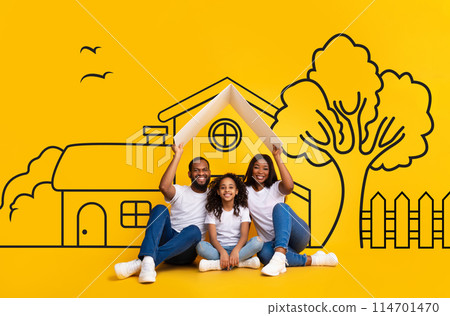A cheerful African American family, is sitting closely together, smiling widely, and posing against a vibrant yellow backdrop with playful drawings of a house 114701470