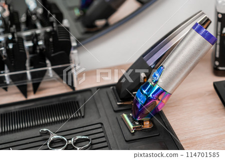 Hair clippers, scissors, and combs are on the table in the barbershop. Hair clippers, scissors, and combs are on the table in the barbershop. 114701585