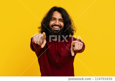 Indian man with long hair and a beard is pointing directly at the camera, making direct eye contact. He appears confident and assertive in his gesture, commanding attention with his presence. 114701650
