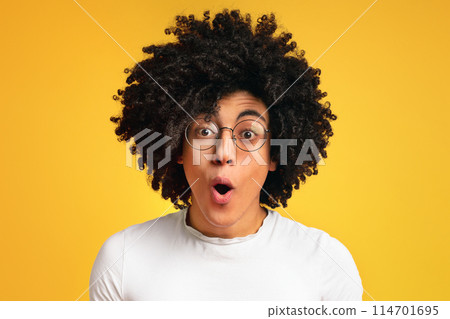 Surprised and shocked curly african-american guy opened mouth in amazement, orange studio background Surprised and shocked curly african-american guy opened mouth in amazement, orange studio background 114701695