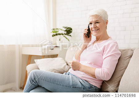 Senior woman talking on her mobile phone, resting on couch, copy space Senior woman talking on her mobile phone, resting on couch, copy space 114701698