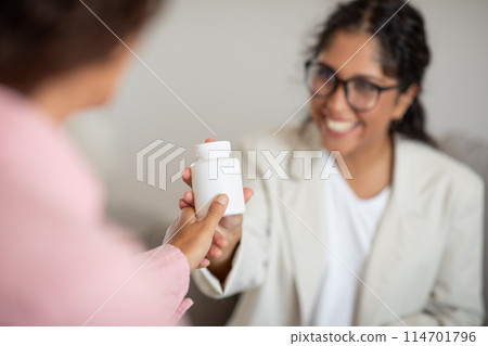 Jar with medication in therapist woman hand. Friendly lady showing her client medication drug pills, recommending supplement for mental health 114701796