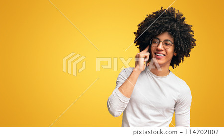 Good mobile connection. Carefree millennial guy talking on cellphone, orange background with empty space 114702002