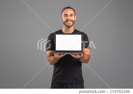 A man is standing, holding a laptop with a blank white screen. The mans hand is grasping the laptop tightly, while his gaze is fixed on the screen. The background is simple and unobtrusive. A man is standing, holding a laptop with a blank white screen. The mans hand is grasping the laptop tightly, while his gaze is fixed on the screen. The background is simple and unobtrusive. 114702206