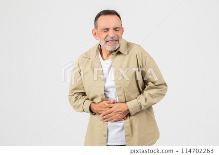 A senior man is shown with his hands placed on his stomach, indicating discomfort or pain. He appears to be experiencing abdominal issues, possibly due to indigestion or illness. A senior man is shown with his hands placed on his stomach, indicating discomfort or pain. He appears to be experiencing abdominal issues, possibly due to indigestion or illness. 114702263