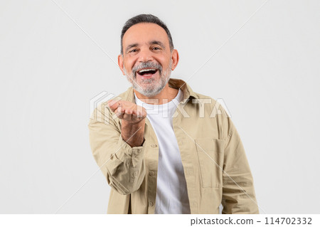 A senior man wearing a tan jacket is contorting his face into a funny expression, possibly for comedic effect or entertainment. He appears to be in a lighthearted and playful mood. A senior man wearing a tan jacket is contorting his face into a funny expression, possibly for comedic effect or entertainment. He appears to be in a lighthearted and playful mood. 114702332