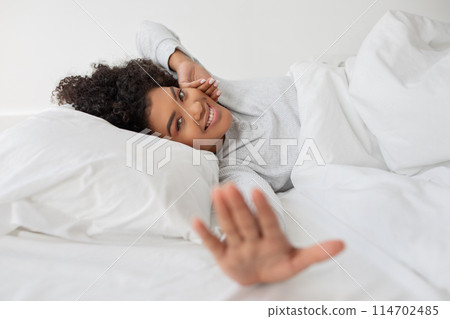 A woman is seen laying in bed with a white blanket covering her body, stretching. She appears to be resting comfortably in a cozy setting. A woman is seen laying in bed with a white blanket covering her body, stretching. She appears to be resting comfortably in a cozy setting. 114702485