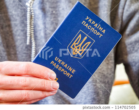 Blue passport with gold emblem, representing Ukrainian identity and global mobility. 114702505