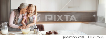 Satisfied old lady in apron hugs little granddaughter, make dough, have fun in minimalist kitchen interior, free space. Hobby at spare time together, cooking lesson baking and prepare food home 114702536