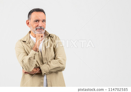 A senior man standing with his hands folded in front of his face in contemplation or prayer. He appears deep in thought, with a focused expression on his face, copy space A senior man standing with his hands folded in front of his face in contemplation or prayer. He appears deep in thought, with a focused expression on his face, copy space 114702585