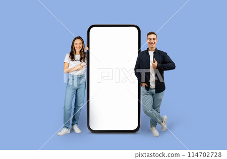 Young man and woman standing next to an enormous mobile mockup screen copy space for advertisement, studio background Young man and woman standing next to an enormous mobile mockup screen copy space for advertisement, studio background 114702728