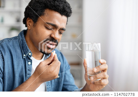 African american guy at home about to take medication, suggesting health care or wellness routine, copy space African american guy at home about to take medication, suggesting health care or wellness routine, copy space 114702778