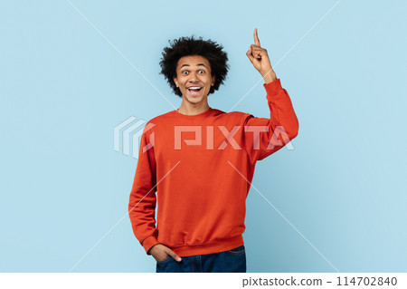 Excited african american man in red sweater with finger pointed up, isolated on a blue background embodying concepts of having an idea or solution Excited african american man in red sweater with finger pointed up, isolated on a blue background embodying concepts of having an idea or solution 114702840