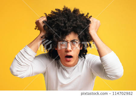 Emotional black guy getting crazy, shouting and rending his hair in stress, orange panorama background 114702982
