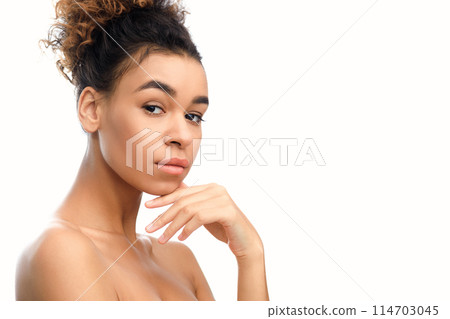 Serene african american woman in thoughtful pose, framed by tropical green leaves, conveying a spa and wellness atmosphere suited for stock use, copy space 114703045