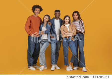 A cheerful, diverse group of five friends smiling and posing for a photo with a warm orange background A cheerful, diverse group of five friends smiling and posing for a photo with a warm orange background 114703061