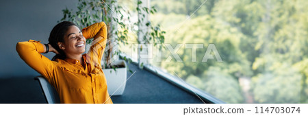 Taking break. Relaxed african american businesswoman resting on chair, leaning back at workplace in office. Happy woman with closed eyes holding hands behind head, panorama with copy space 114703074