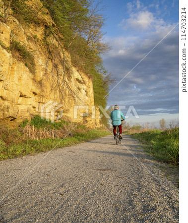 male cyclist riding a folding bike on Steamboat Trace, bike trail converted from an abandoned railroad, near Peru, Nebraska, springtime morning scenery 114703214