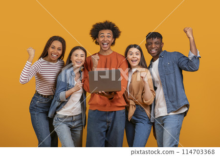 An excited international team of friends collectively looking at a laptop screen, embodying multiethnic, multiracial teamwork and success isolated on orange An excited international team of friends collectively looking at a laptop screen, embodying multiethnic, multiracial teamwork and success isolated on orange 114703368