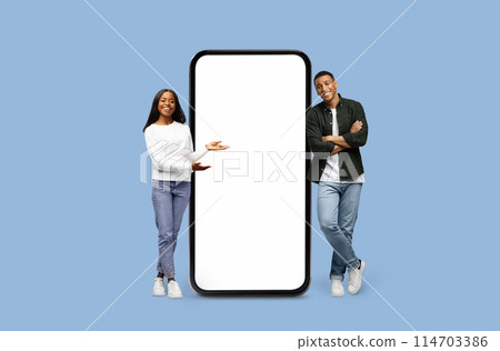 African American woman presents while the man observes a blank smartphone screen mockup copy space on blue 114703386