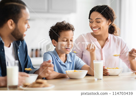 African American family enjoying a healthy breakfast together in a bright kitchen, showcasing family bonding African American family enjoying a healthy breakfast together in a bright kitchen, showcasing family bonding 114703439