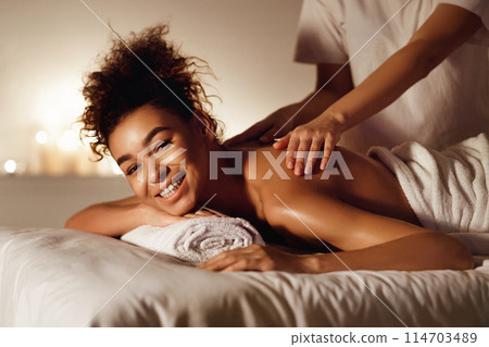 Health spa. Beautiful girl enjoying back massage smiling at camera 114703489