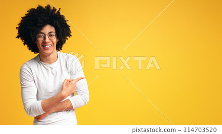 Look here. Awesome black guy in glasses pointing away at copy space, showing new offer on orange panorama background 114703520