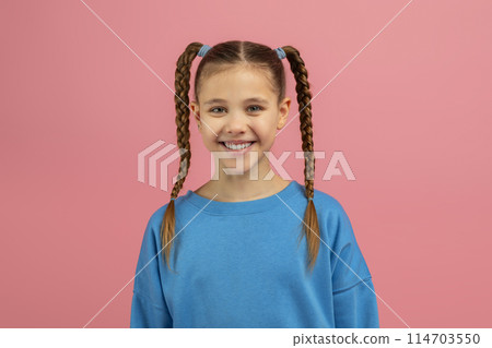 A cheerful teen girl with long braided pigtails smiling at the camera, isolated on a pink background, showcasing a caucasian youngster's happiness A cheerful teen girl with long braided pigtails smiling at the camera, isolated on a pink background, showcasing a caucasian youngster's happiness 114703550