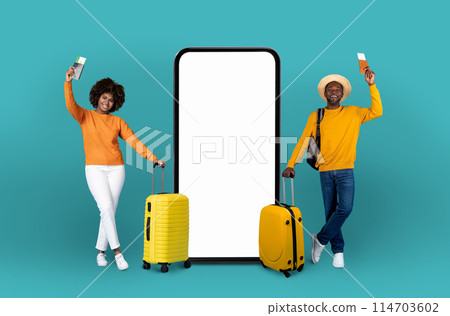 Playful african american couple in yellow stands by an oversized smartphone screen, illustrating the integration of travel with digital technology 114703602