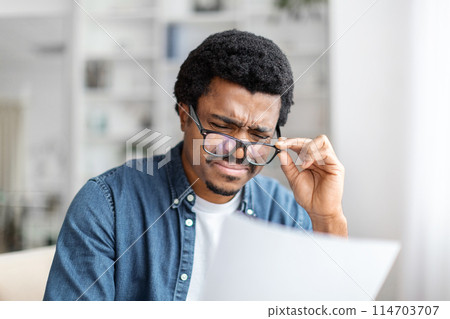 An african american guy is deeply engrossed in reviewing paperwork, signifying diligence and responsibility management An african american guy is deeply engrossed in reviewing paperwork, signifying diligence and responsibility management 114703707