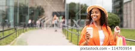 Cheerful young african american lady in casual, hat with many bags with purchases enjoy cup of coffee takeaway, look at free space on city street. Shopaholic, shopping, sale and favorite drink outdoor 114703954
